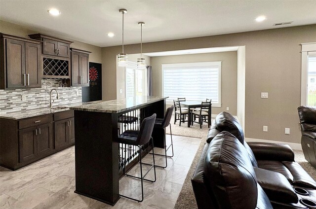 17595 Aurora Dr, Clive, IA 50325 - kitchen with dark brown cabinetry, decorative backsplash, light stone countertops, plenty of natural light, and recessed lighting