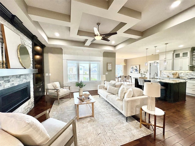 17595 Aurora Dr, Clive, IA 50325 - living room featuring a ceiling fan, dark wood-style flooring, a stone fireplace, coffered ceiling, and recessed lighting