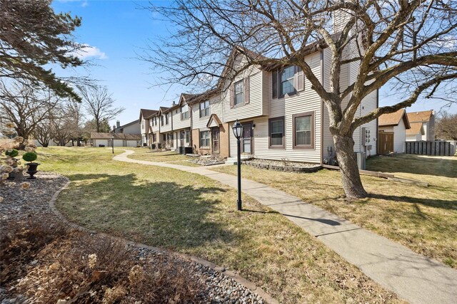 exterior space with a residential view, a front yard, central AC, and fence