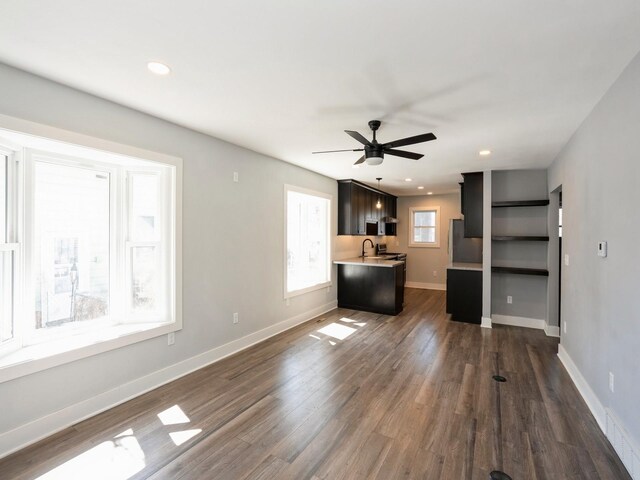 613 E 8th St N, Newton, IA 50208 - unfurnished living room with dark wood-style flooring, a ceiling fan, baseboards, recessed lighting, and a sink