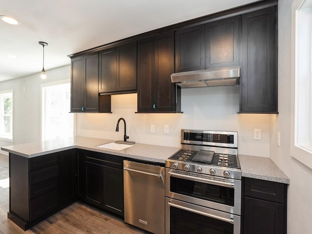 613 E 8th St N, Newton, IA 50208 - kitchen featuring appliances with stainless steel finishes, under cabinet range hood, a sink, dark wood-type flooring, and a peninsula