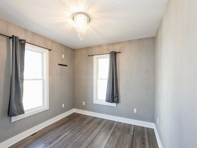 613 E 8th St N, Newton, IA 50208 - spare room featuring a chandelier, plenty of natural light, dark wood-style floors, and baseboards