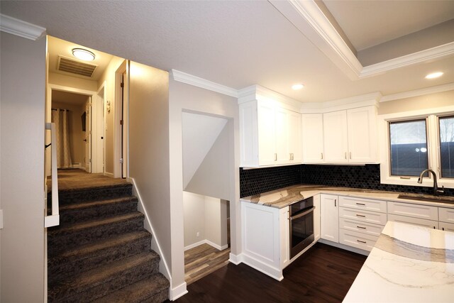 kitchen featuring visible vents, light stone countertops, a sink, and oven