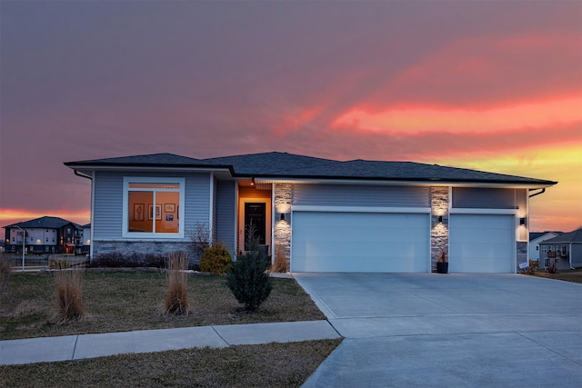prairie-style house featuring stone siding, driveway, and a garage
