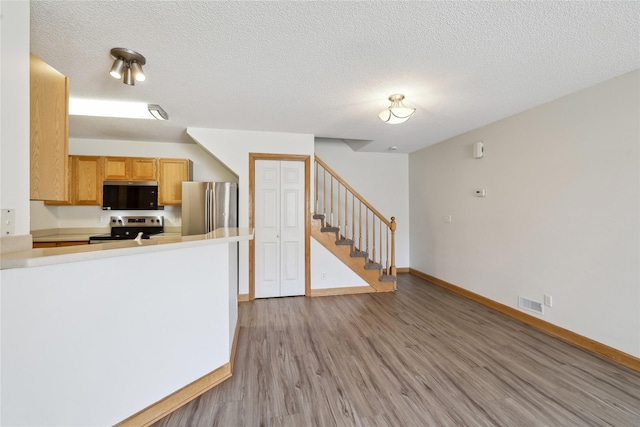 811 Burr Oaks Dr Unit 1110, West Des Moines, IA 50266 - kitchen with stainless steel appliances, light wood finished floors, a textured ceiling, a peninsula, and light countertops