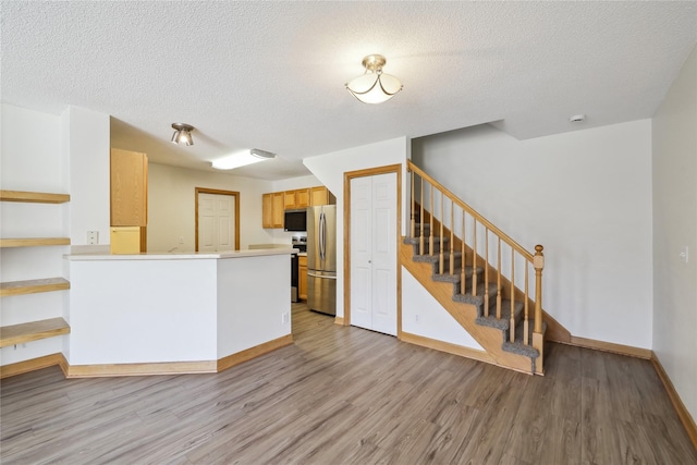 811 Burr Oaks Dr Unit 1110, West Des Moines, IA 50266 - kitchen featuring stainless steel appliances, light wood-style flooring, a textured ceiling, a peninsula, and light countertops