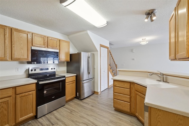 811 Burr Oaks Dr Unit 1110, West Des Moines, IA 50266 - kitchen with appliances with stainless steel finishes, light wood finished floors, a textured ceiling, a peninsula, and light countertops