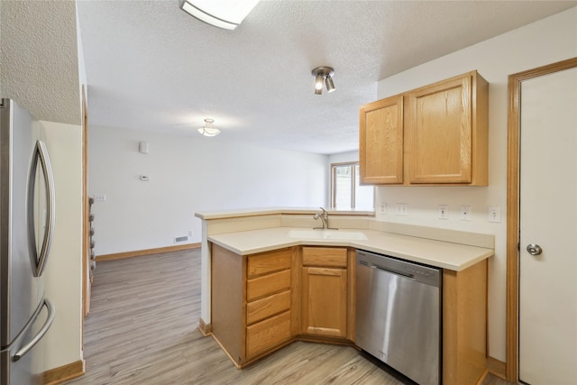 811 Burr Oaks Dr Unit 1110, West Des Moines, IA 50266 - kitchen with stainless steel appliances, a peninsula, a textured ceiling, light wood-type flooring, and light countertops