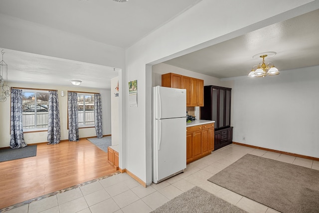 400 Center Ave S, Mitchellville, IA 50169 - kitchen with freestanding refrigerator, light tile patterned floors, a chandelier, and baseboards