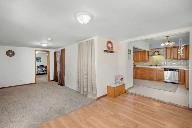 400 Center Ave S, Mitchellville, IA 50169 - unfurnished living room featuring a chandelier, light wood-type flooring, baseboards, and a sink