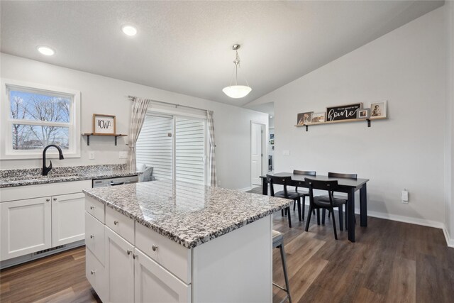 kitchen with white cabinetry, vaulted ceiling, dark wood-style flooring, a center island, and a sink