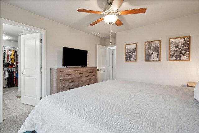 carpeted bedroom featuring a closet, ceiling fan, visible vents, and a walk in closet