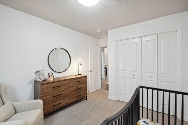 bedroom featuring light carpet, a closet, and a textured ceiling
