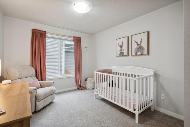 bedroom with carpet floors, a nursery area, baseboards, and a textured ceiling