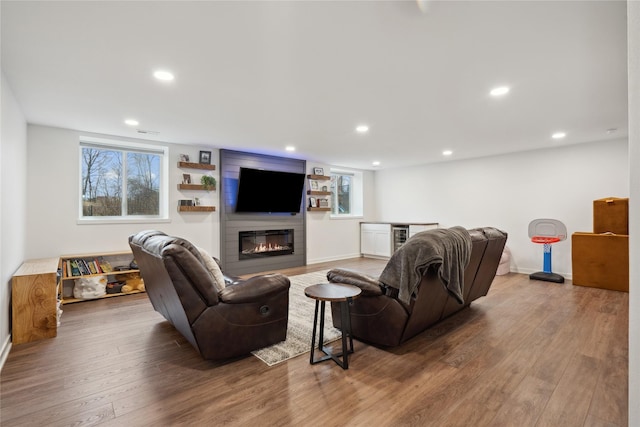 living area featuring a large fireplace, wood finished floors, plenty of natural light, and beverage cooler