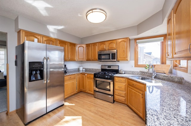 15026 Hawthorn Dr, Clive, IA 50325 - kitchen featuring stainless steel appliances, light stone counters, a sink, and light wood-style flooring