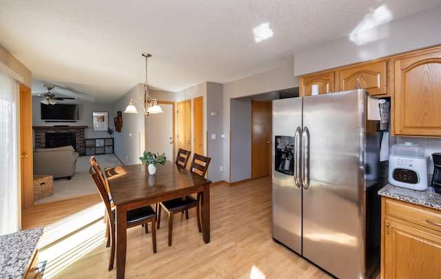 15026 Hawthorn Dr, Clive, IA 50325 - dining room featuring a brick fireplace, light wood-style flooring, a ceiling fan, and a textured ceiling