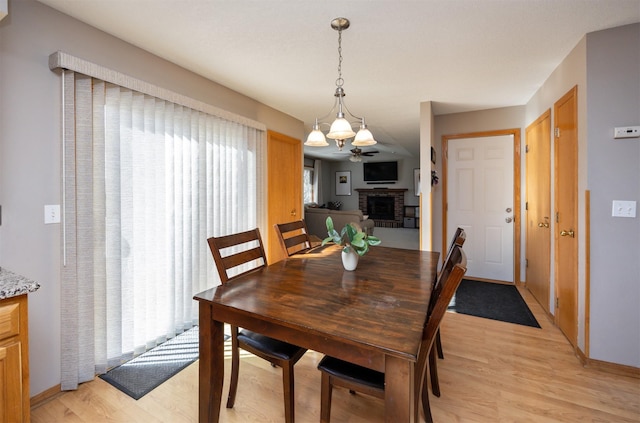 15026 Hawthorn Dr, Clive, IA 50325 - dining area featuring a brick fireplace, light wood-type flooring, and baseboards