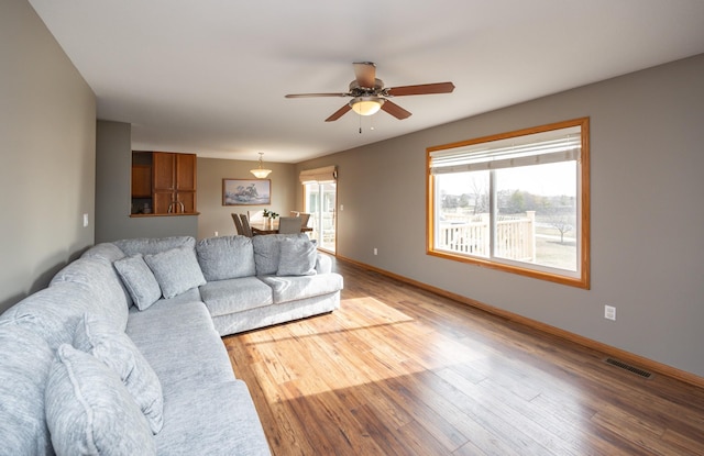 living area with ceiling fan, light wood-style flooring, and baseboards