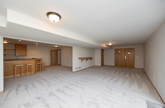 4328 125th St, Urbandale, IA 50323 - unfurnished living room with wet bar, light carpet, and baseboards
