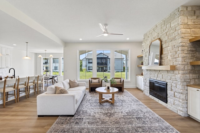 1284 NW 29th Ct, Grimes, IA 50111 - living area with a ceiling fan, plenty of natural light, a stone fireplace, light wood-type flooring, and recessed lighting