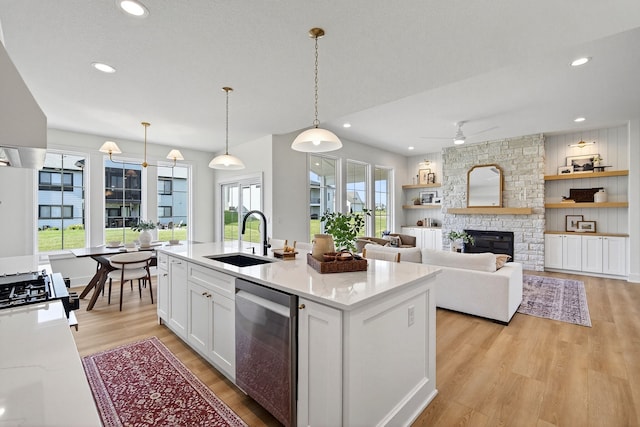 1284 NW 29th Ct, Grimes, IA 50111 - kitchen featuring dishwasher, ceiling fan, white cabinetry, light wood finished floors, and a stone fireplace