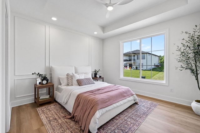 1284 NW 29th Ct, Grimes, IA 50111 - bedroom with light wood-style flooring, a raised ceiling, recessed lighting, and a ceiling fan