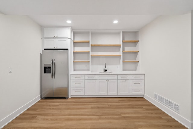 1284 NW 29th Ct, Grimes, IA 50111 - kitchen with stainless steel fridge, white cabinetry, open shelves, light countertops, and light wood finished floors