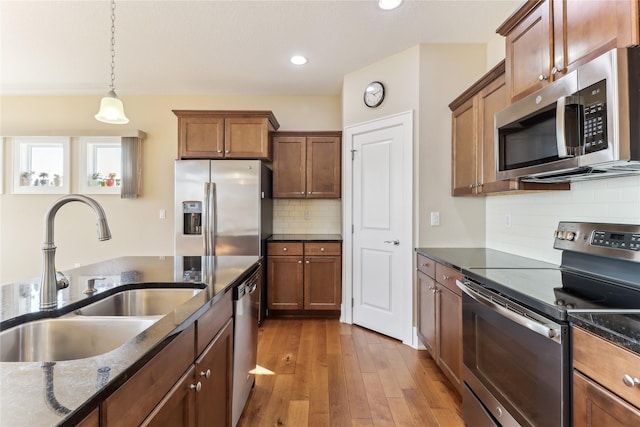 7821 NW 96th St, Johnston, IA 50131 - kitchen featuring appliances with stainless steel finishes, a sink, hardwood / wood-style floors, dark stone countertops, and recessed lighting