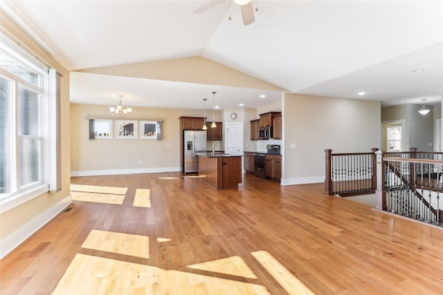 7821 NW 96th St, Johnston, IA 50131 - unfurnished living room with a sink, light wood-style floors, lofted ceiling, a chandelier, and a ceiling fan