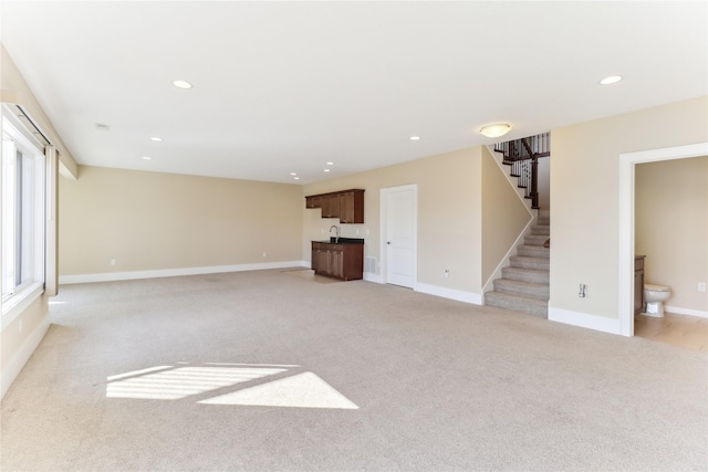 7821 NW 96th St, Johnston, IA 50131 - unfurnished living room with light carpet, stairway, recessed lighting, baseboards, and a sink