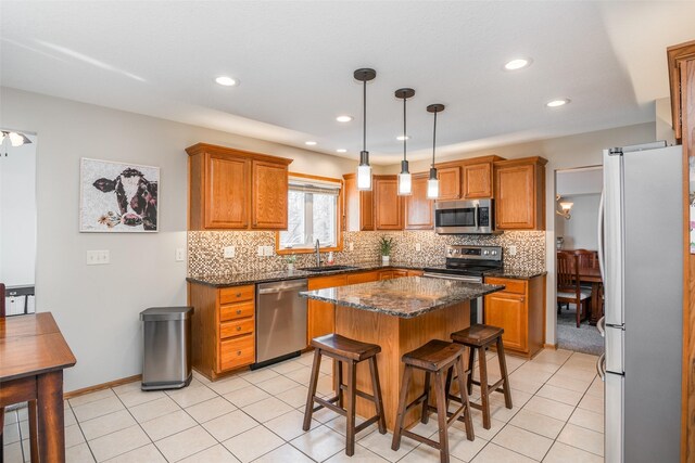 4850 Augusta Ln, Pleasant Hill, IA 50327 - kitchen featuring appliances with stainless steel finishes, brown cabinets, a breakfast bar, tasteful backsplash, and a center island