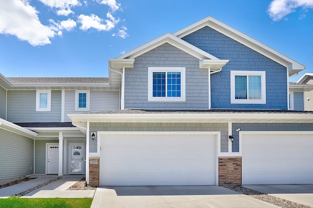 view of property featuring a garage, driveway, and stone siding