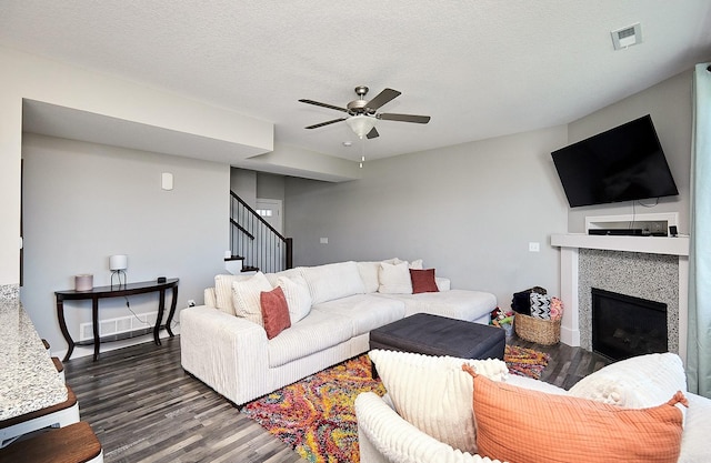living room featuring stairs, a ceiling fan, a glass covered fireplace, and dark wood-type flooring