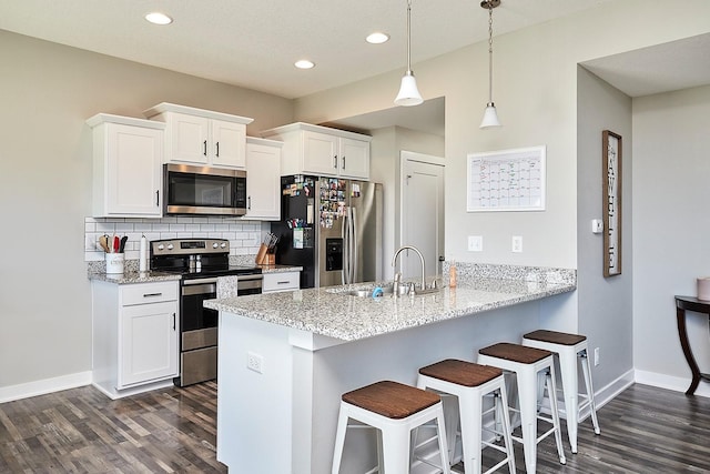 kitchen featuring dark wood-style flooring, a breakfast bar area, stainless steel appliances, and a sink