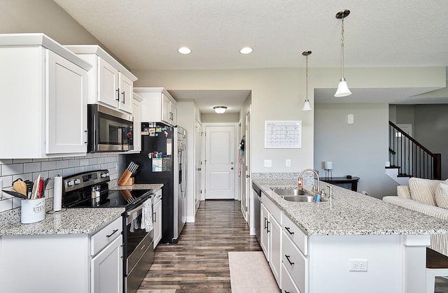 kitchen featuring a sink, a breakfast bar area, stainless steel appliances, white cabinets, and dark wood-style floors