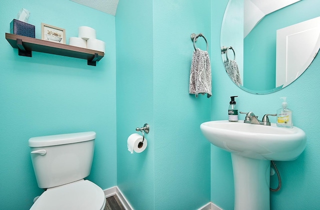 half bathroom featuring toilet, wood finished floors, and baseboards