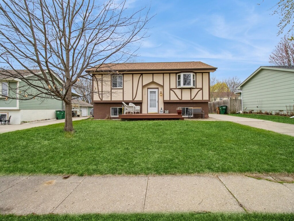 1245 S 5th St, Carlisle, IA 50047 - split foyer home featuring brick siding, a front yard, fence, and a wooden deck