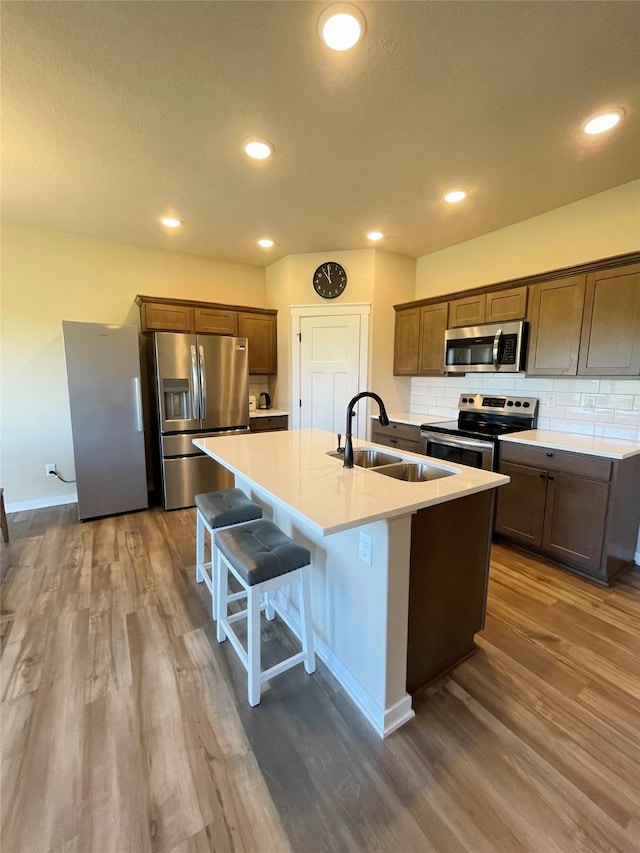 425 SE Hollow Ct, West Des Moines, IA 50265 - kitchen with dark wood-style flooring, a center island with sink, a sink, appliances with stainless steel finishes, and backsplash