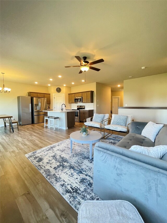 425 SE Hollow Ct, West Des Moines, IA 50265 - living room with recessed lighting, ceiling fan with notable chandelier, and light wood-type flooring