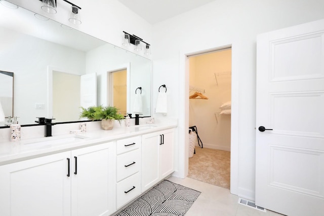 full bathroom featuring a walk in closet, visible vents, a sink, and double vanity