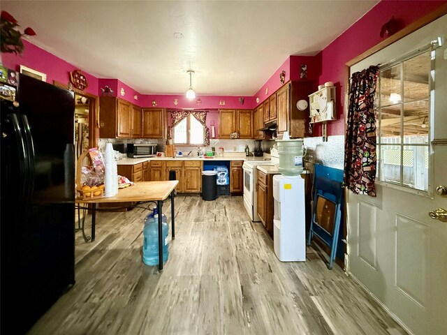 603 E Church St, Marshalltown, IA 50158 - kitchen featuring light countertops, light wood-style floors, white range with electric stovetop, brown cabinetry, and freestanding refrigerator
