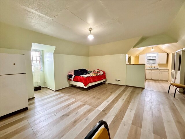 603 E Church St, Marshalltown, IA 50158 - bedroom featuring a sink, freestanding refrigerator, light wood-type flooring, lofted ceiling, and visible vents