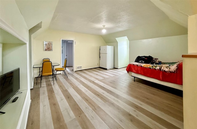 603 E Church St, Marshalltown, IA 50158 - bedroom with freestanding refrigerator, lofted ceiling, light wood-type flooring, baseboards, and visible vents