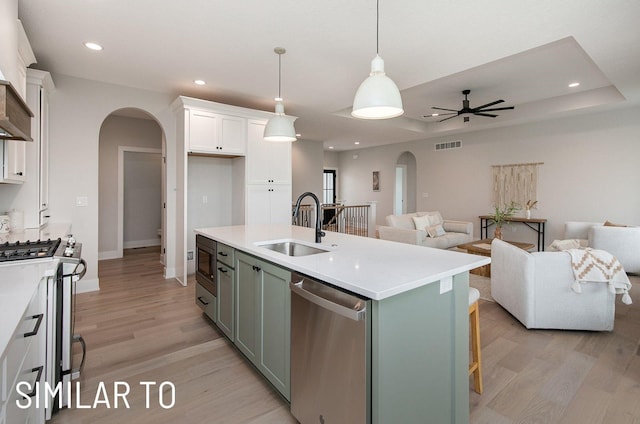 18048 Tanglewood Dr, Clive, IA 50325 - kitchen featuring arched walkways, appliances with stainless steel finishes, open floor plan, white cabinets, and light wood-style flooring