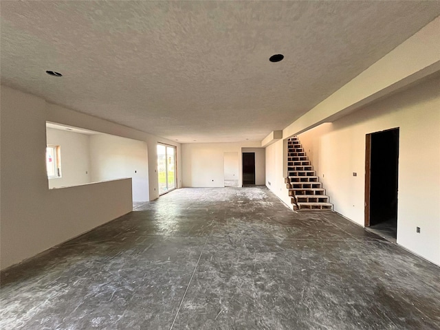18048 Tanglewood Dr, Clive, IA 50325 - unfurnished living room featuring a textured ceiling and stairway