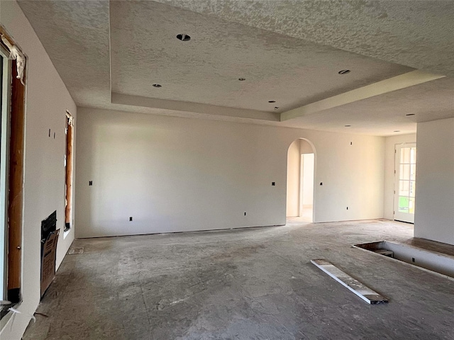 18048 Tanglewood Dr, Clive, IA 50325 - unfurnished living room featuring a tray ceiling, a textured ceiling, and arched walkways