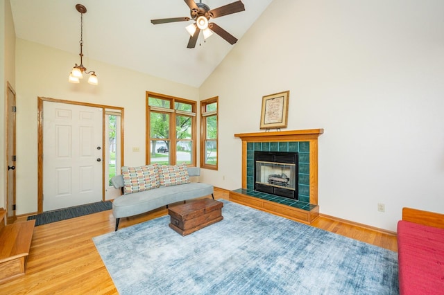 4774 Coachlight Dr, West Des Moines, IA 50265 - living room featuring wood finished floors, high vaulted ceiling, a ceiling fan, and a tiled fireplace