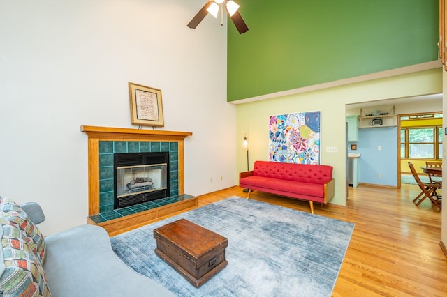4774 Coachlight Dr, West Des Moines, IA 50265 - living room featuring a towering ceiling, a ceiling fan, wood finished floors, and a fireplace