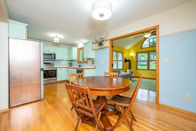 4774 Coachlight Dr, West Des Moines, IA 50265 - dining area with a wood stove, ceiling fan, light wood-style flooring, lofted ceiling, and baseboards